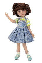 Doll wearing a blue denim dress with a yellow shirt on a white background