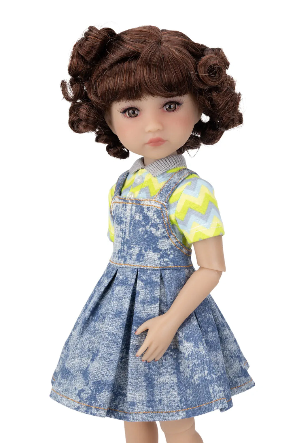 Doll wearing a blue denim dress with a yellow and green patterned top on a white background