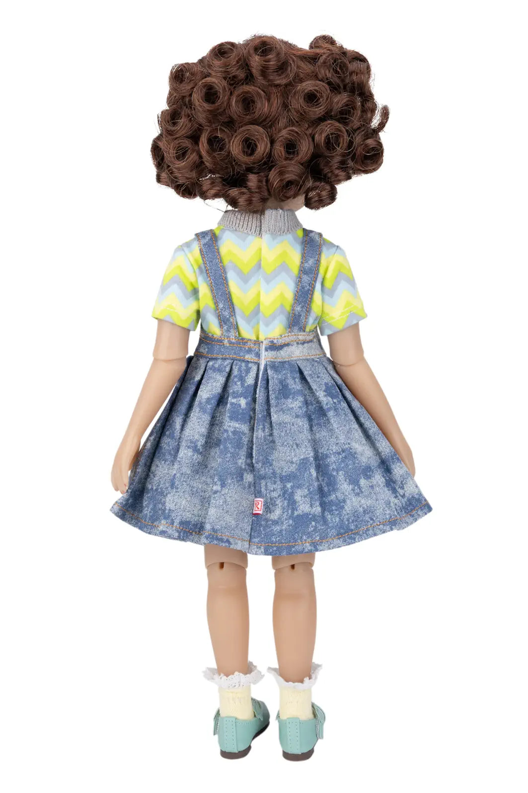 Doll with curly hair wearing a yellow and blue outfit on a white background