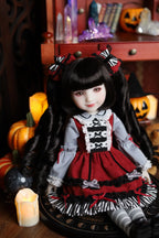 Doll in a red and black outfit with Halloween decorations in the background