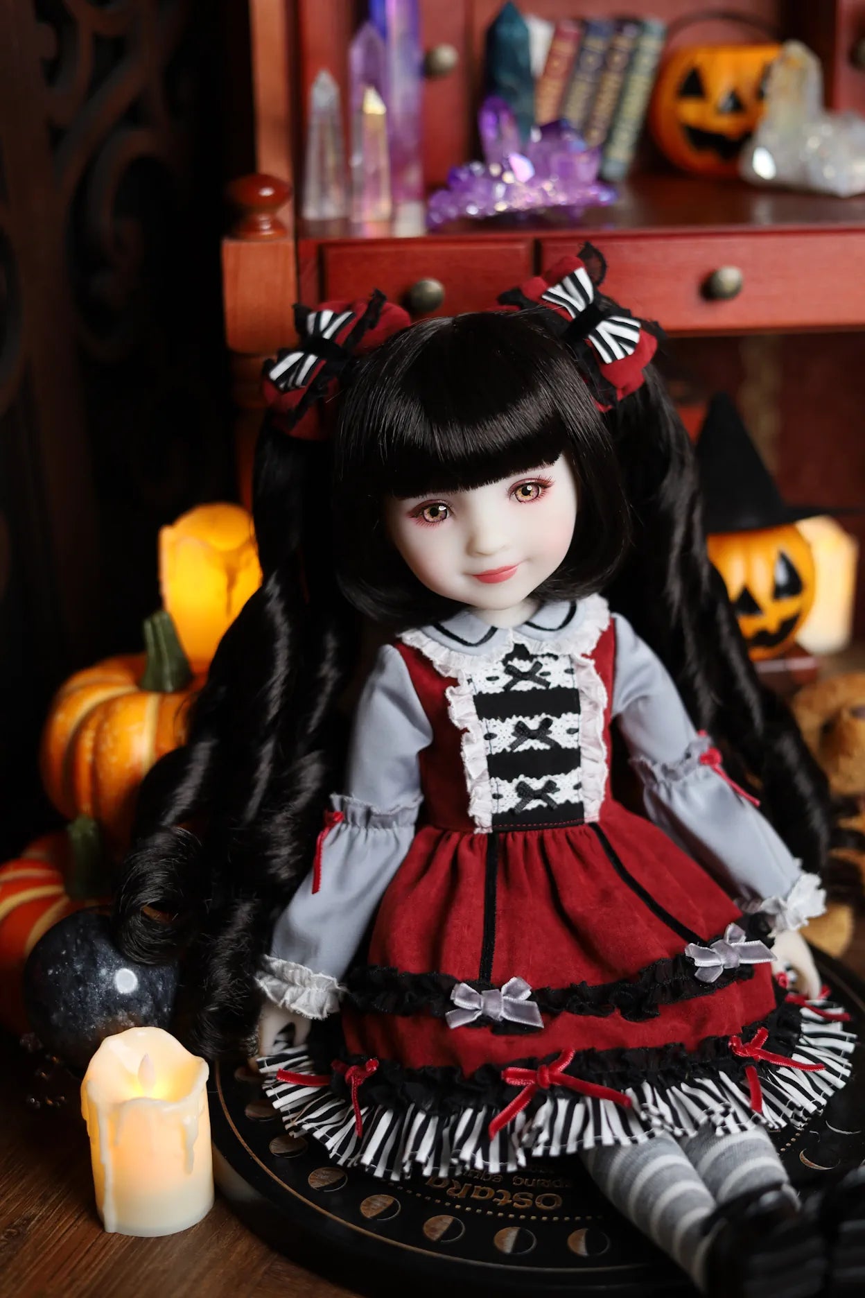 Doll in a red and black outfit with Halloween decorations in the background