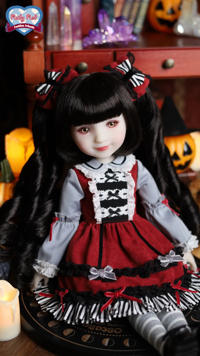 Doll with black hair and a red and white outfit in a Halloween-themed setting