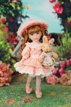 Doll in a pink dress holding a rabbit plush toy in a garden setting