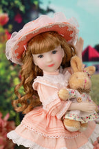 Doll in a pink dress and hat holding a  rabbit plush toy with a blurred outdoor background