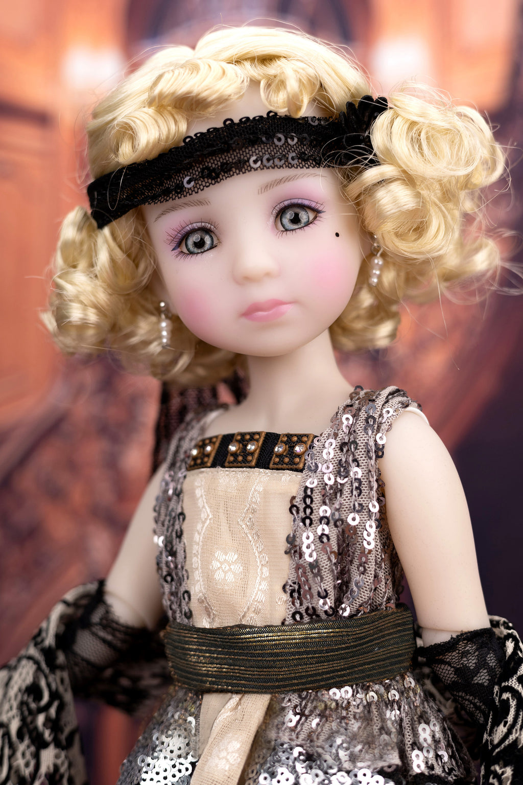 Doll with blonde hair and a sequined dress against a blurred background