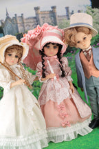 Three dolls in vintage clothing with a castle in the background