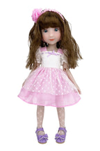Doll with long brown hair wearing a pink dress with white polka dots on a white background