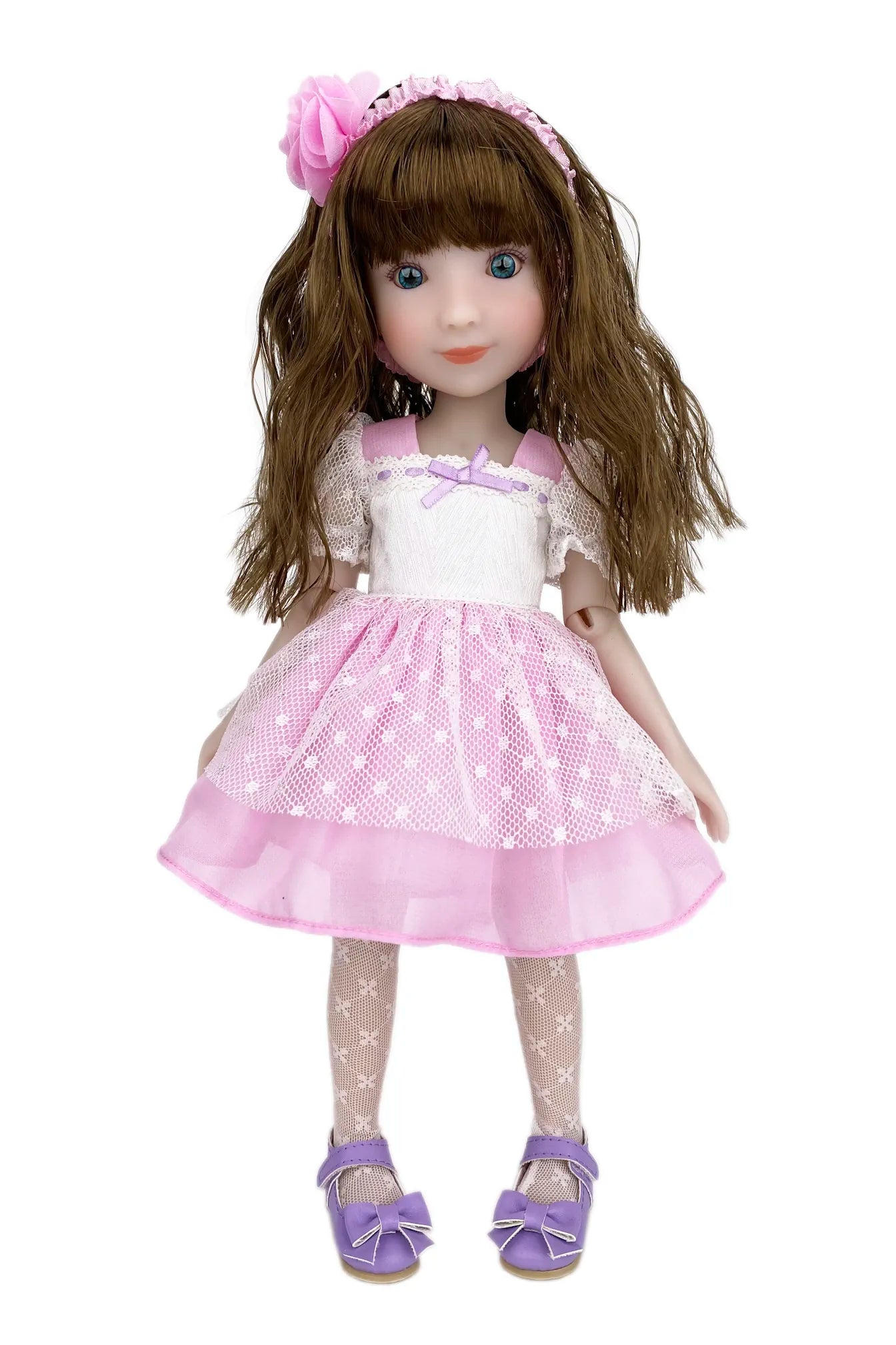Doll with long brown hair wearing a pink dress with white polka dots on a white background