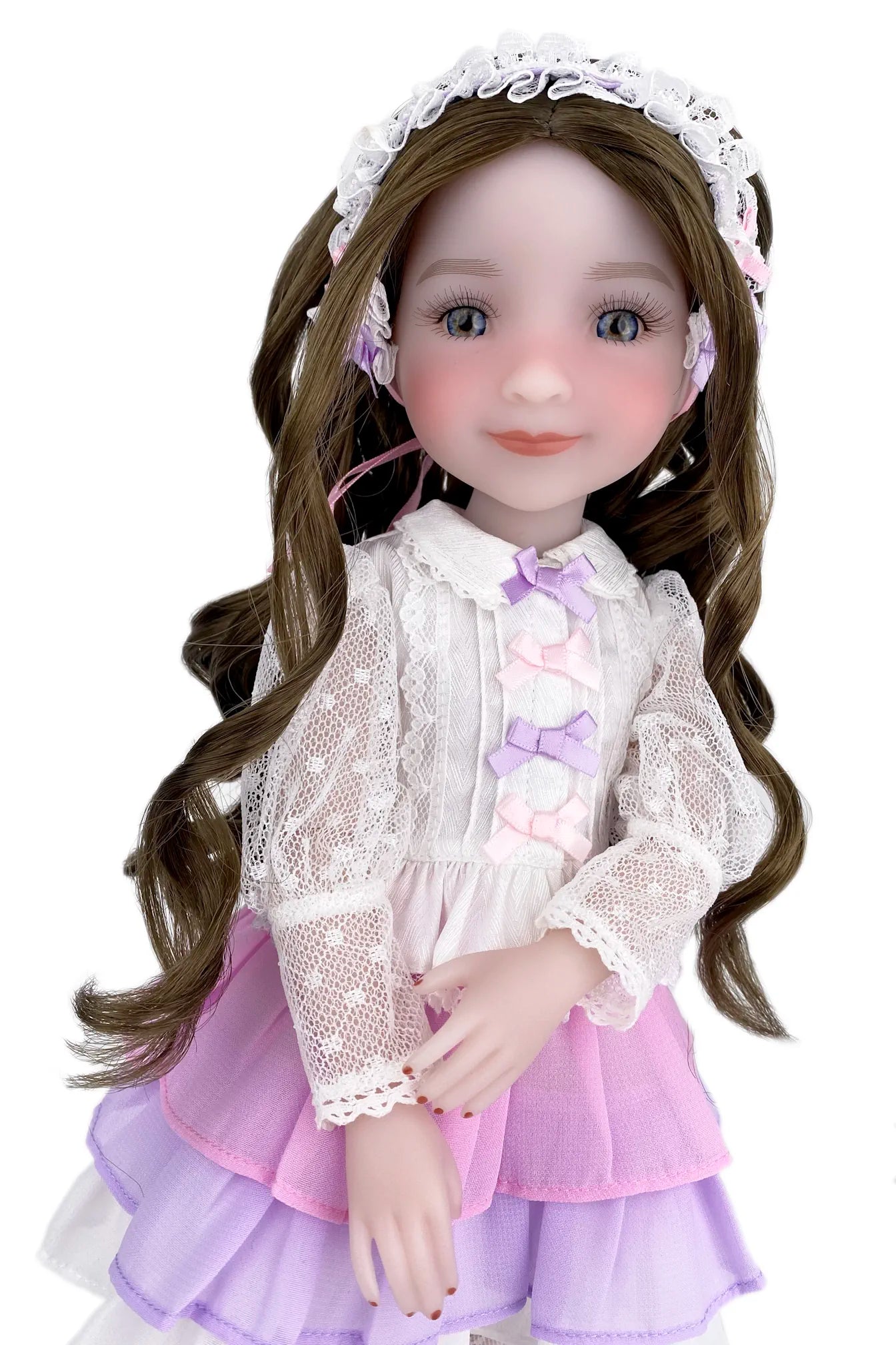 Doll with long brown hair wearing a white lace top and pink skirt on a white background
