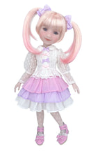 Doll with pink hair styled in pigtails, wearing a white blouse with lace sleeves and a layered skirt on a white background.