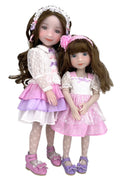 Two dolls in matching outfits with pink and white dresses on a white background