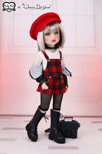 Doll wearing a red beret, plaid dress, and black boots with a small handbag.