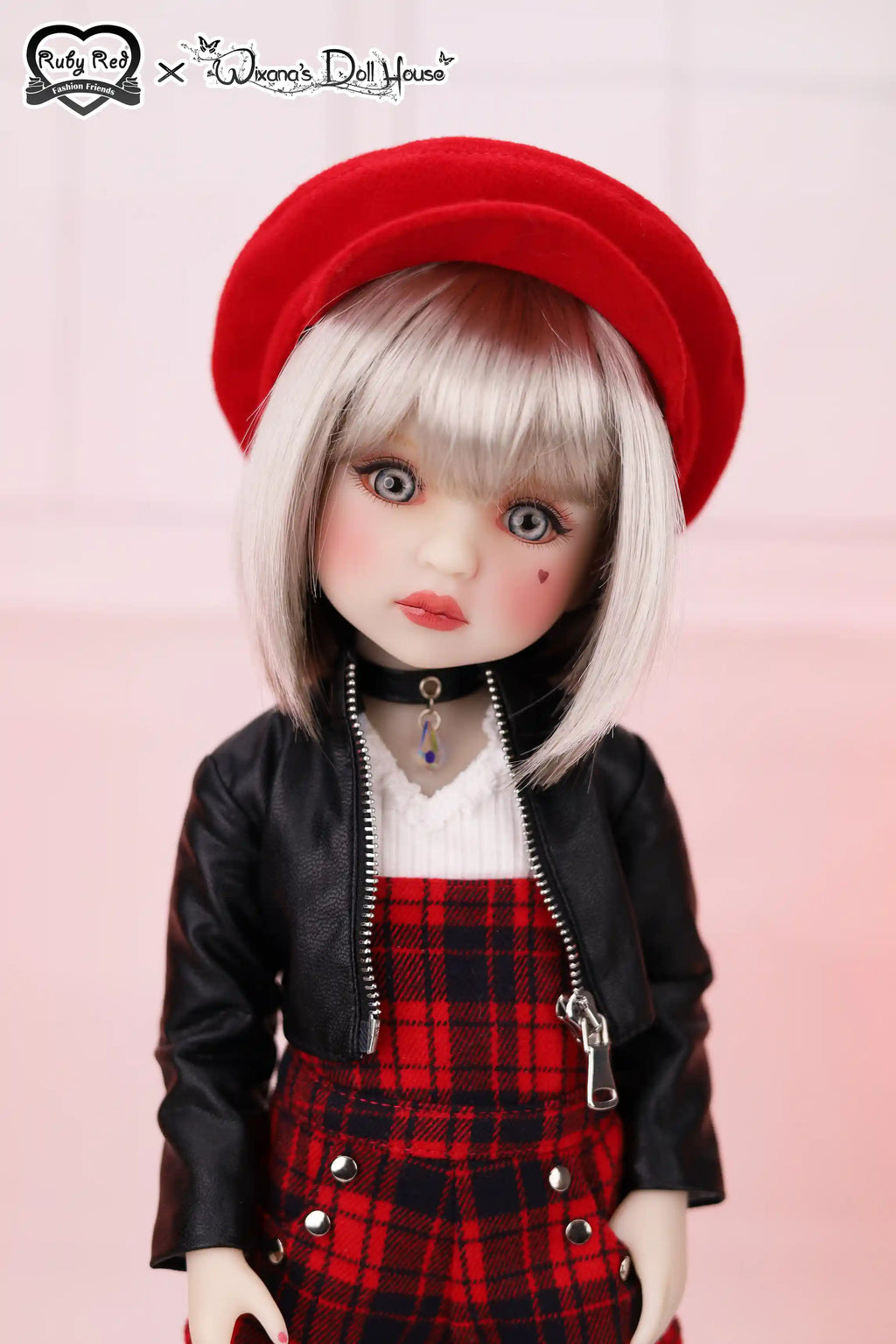 Doll with red hat, black jacket, and plaid skirt on a pink background