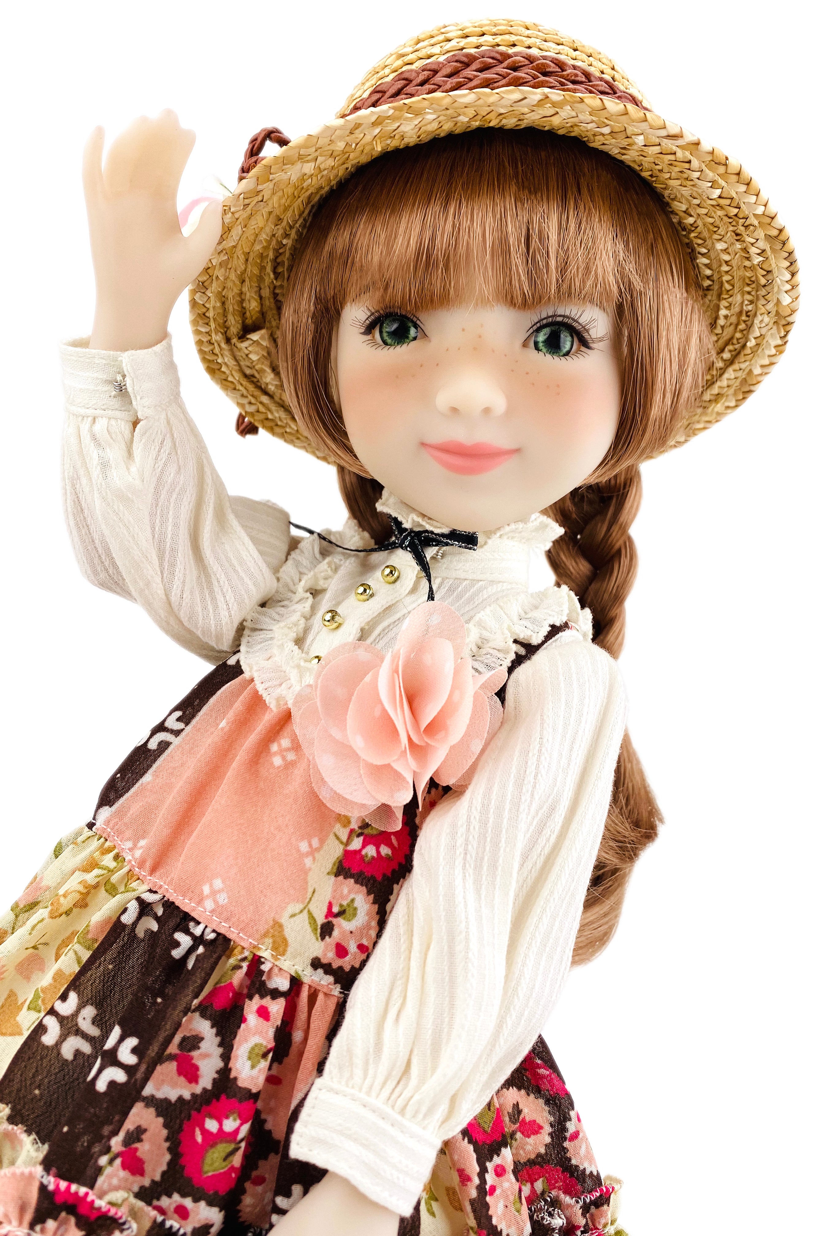 Doll wearing a straw hat and floral dress on a white background