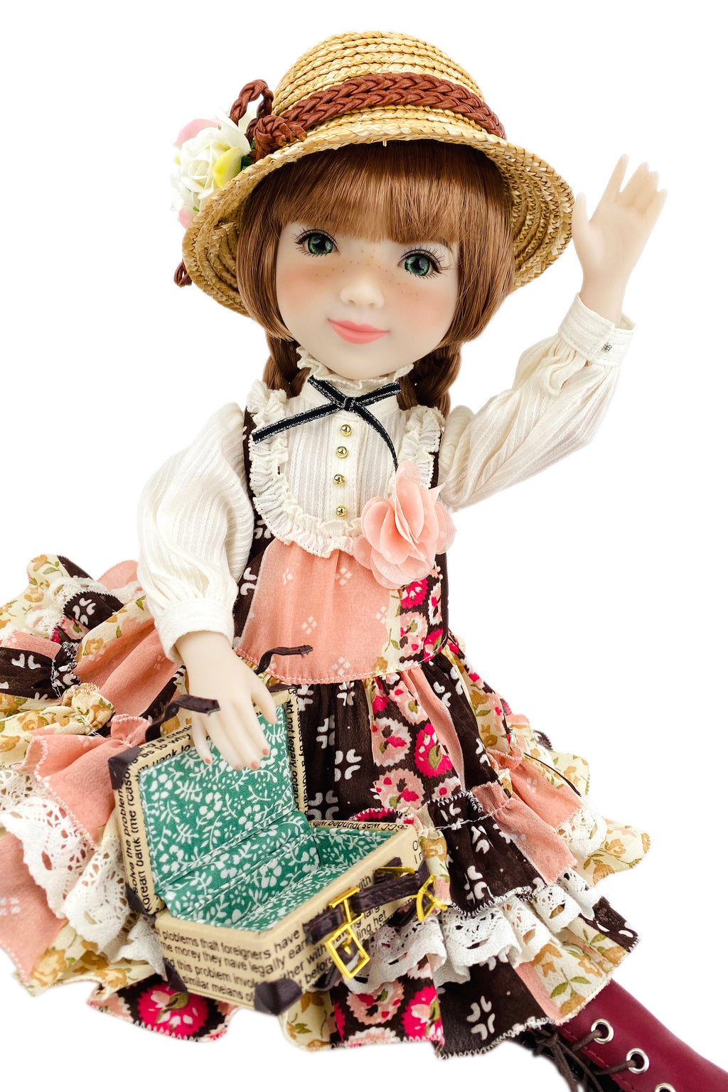 Doll in vintage outfit with hat and suitcase on a white background