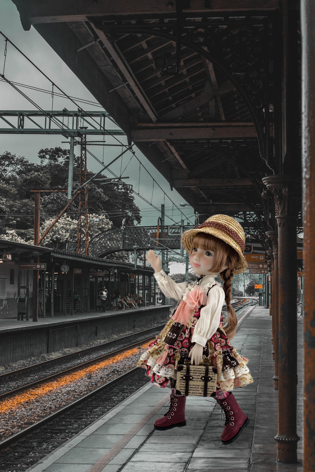 Doll in a vintage dress and hat standing on a train platform.