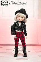 Doll wearing a black leather jacket, red plaid pants, and black hat on a pink background
