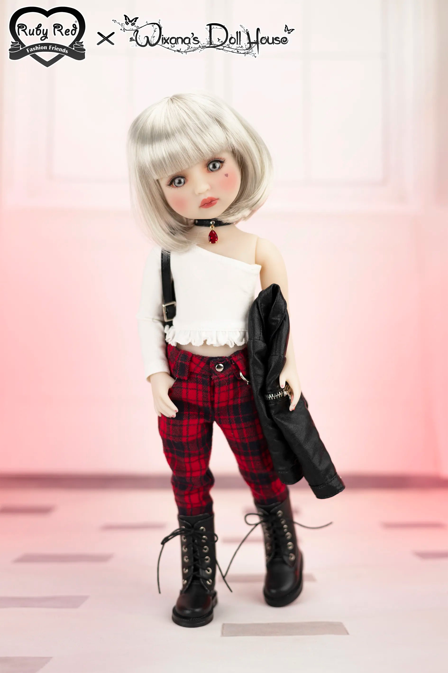 Doll with white hair and plaid pants standing against a light pink background