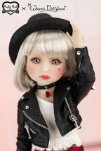 Doll wearing a black jacket and hat with a pink background