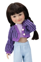 Doll wearing a purple cardigan over a pink shirt with light blue pants on a white background