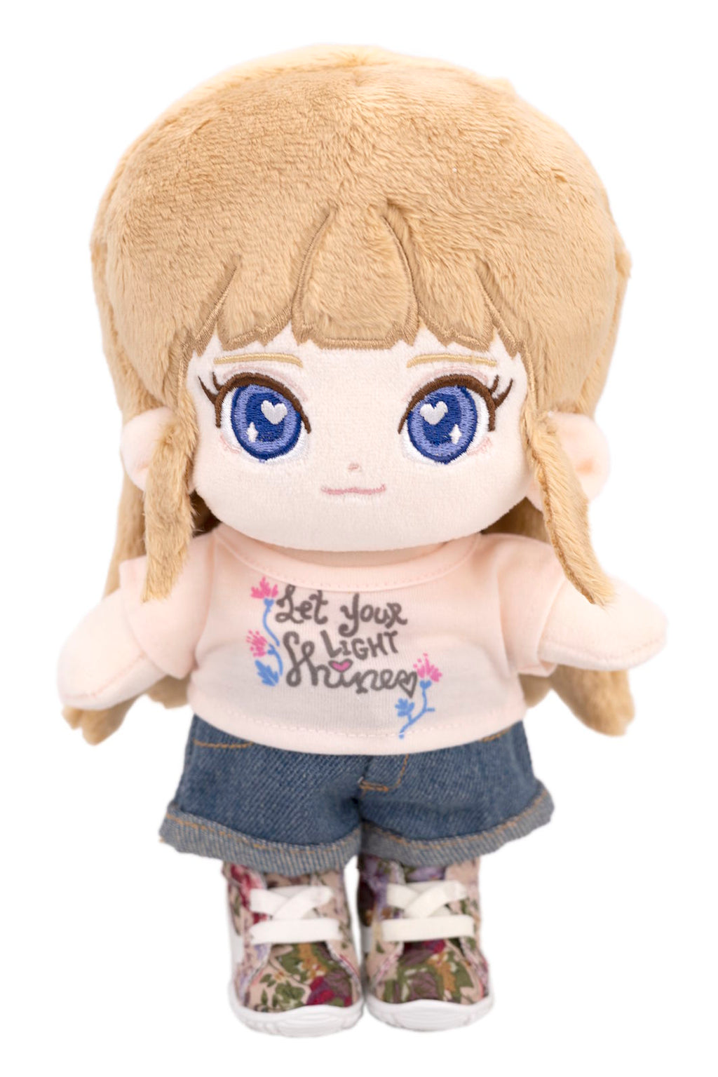Fluffy Sara plush toy with blonde hair and blue eyes, wearing a white shirt with text and denim shorts.