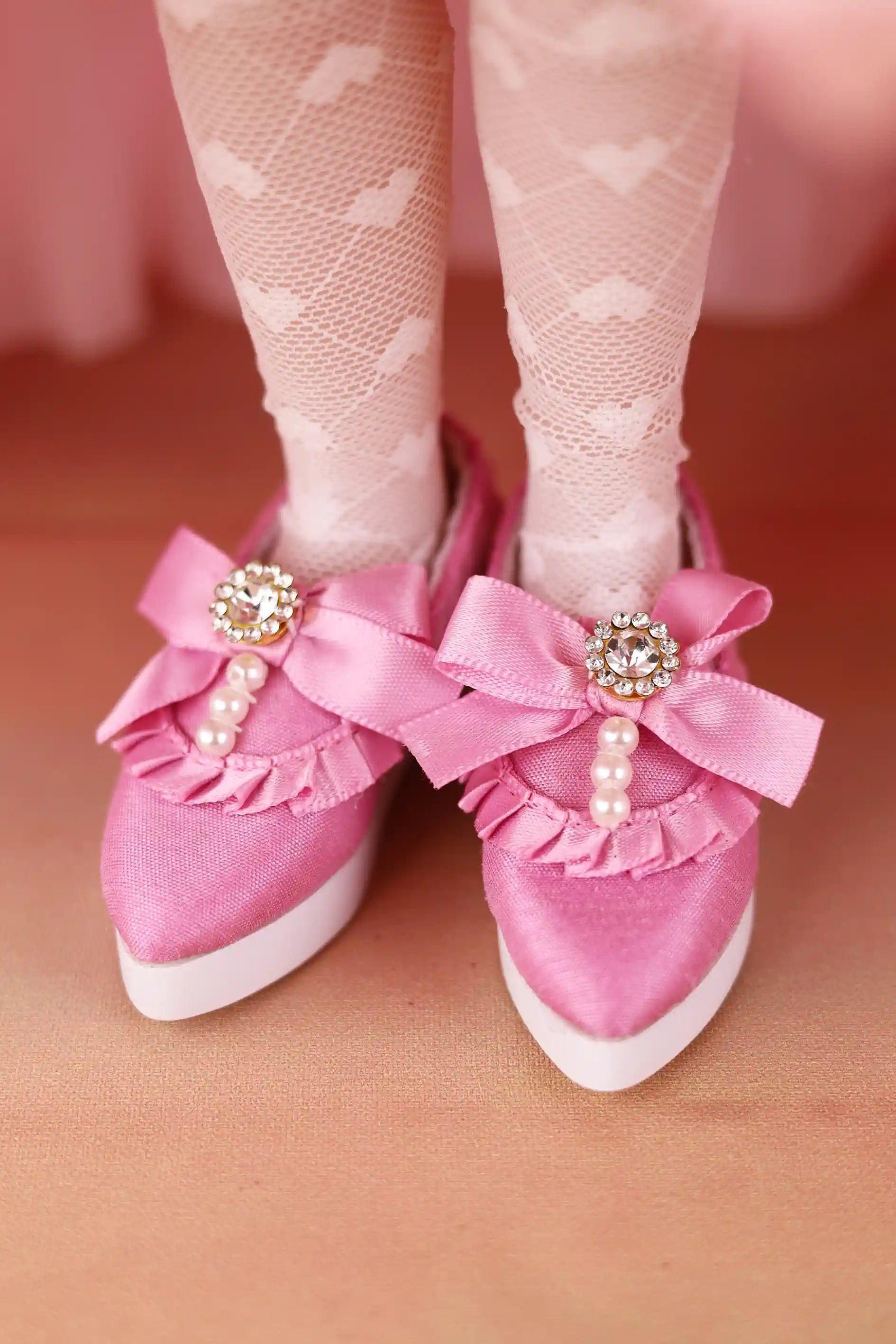 Pink shoes with decorative bows and embellishments on a pink background