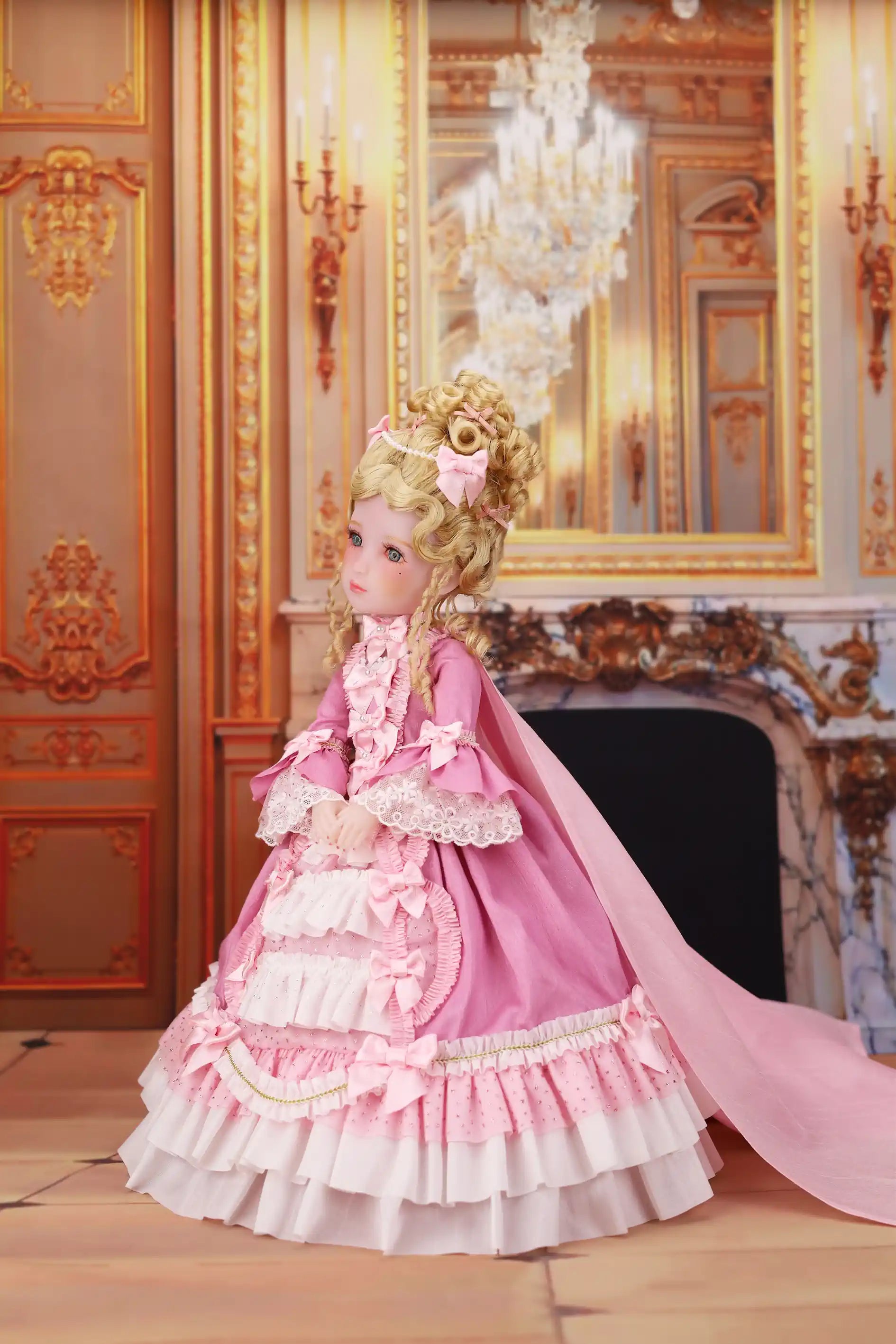 Doll in a pink and white dress standing in an ornate room with a chandelier.