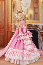 Doll in a pink dress with ruffles in an ornate room.