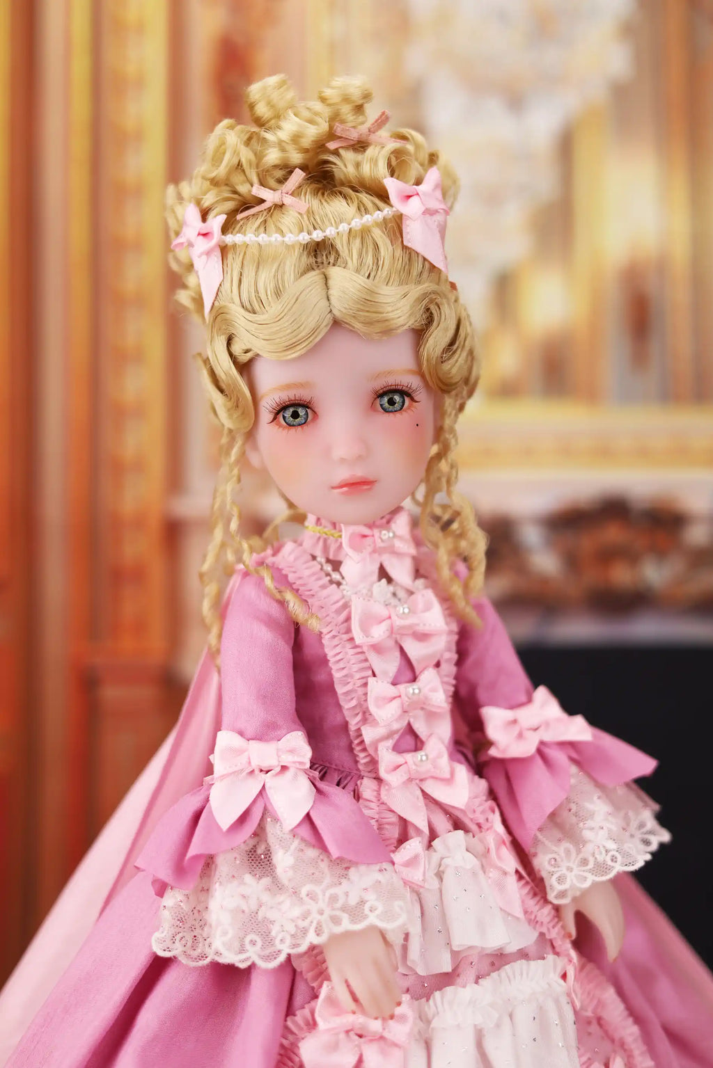 Doll in a pink dress with ruffles and bows against a blurred background