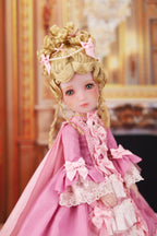 Doll in a pink dress with decorative elements against a blurred background