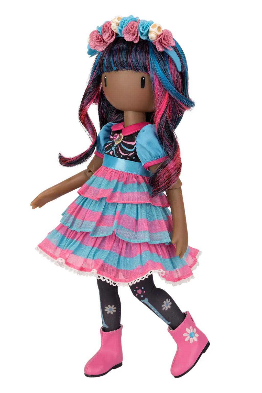 A doll with dark brown skin and long, wavy blue and pink hair, wearing a tiered pink and blue dress, black tights with white flower patterns, pink boots, and a matching flower crown, shown against a plain white background.