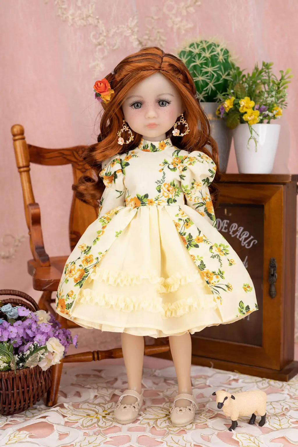 Doll in a floral dress sitting on a chair with flowers and a sheep toy in the background.