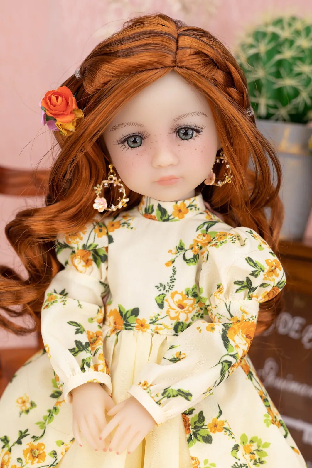 Doll with long red hair and floral dress against a blurred background
