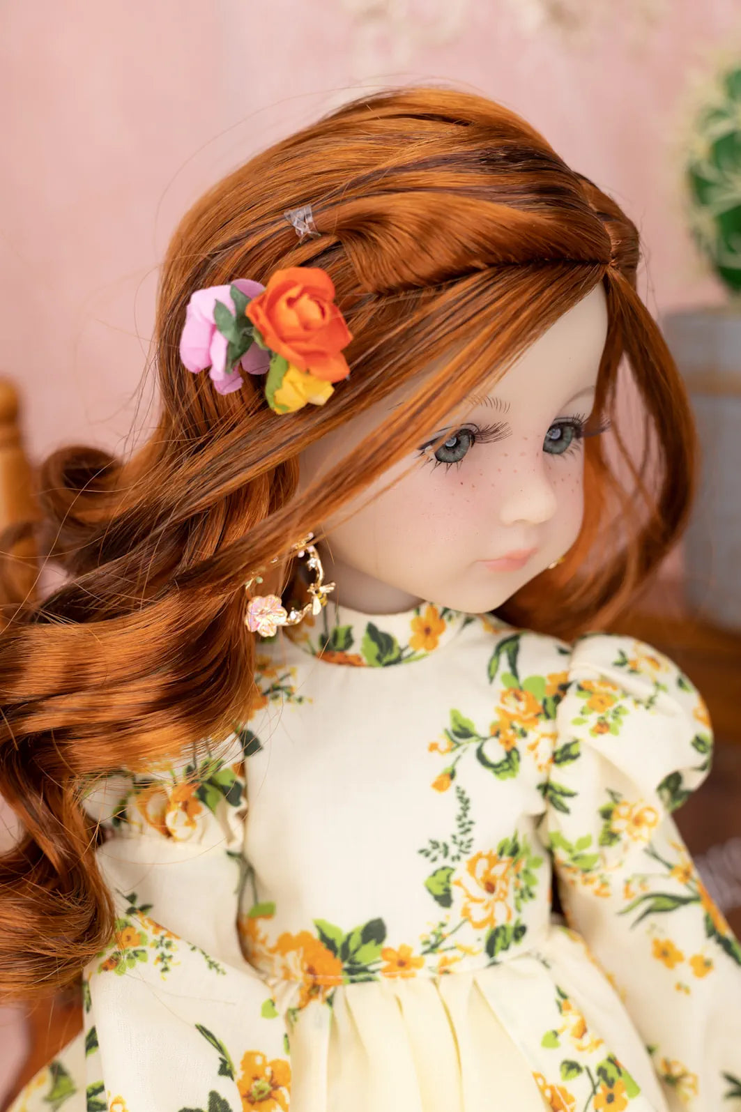 Doll with red hair and floral headband wearing a floral dress.