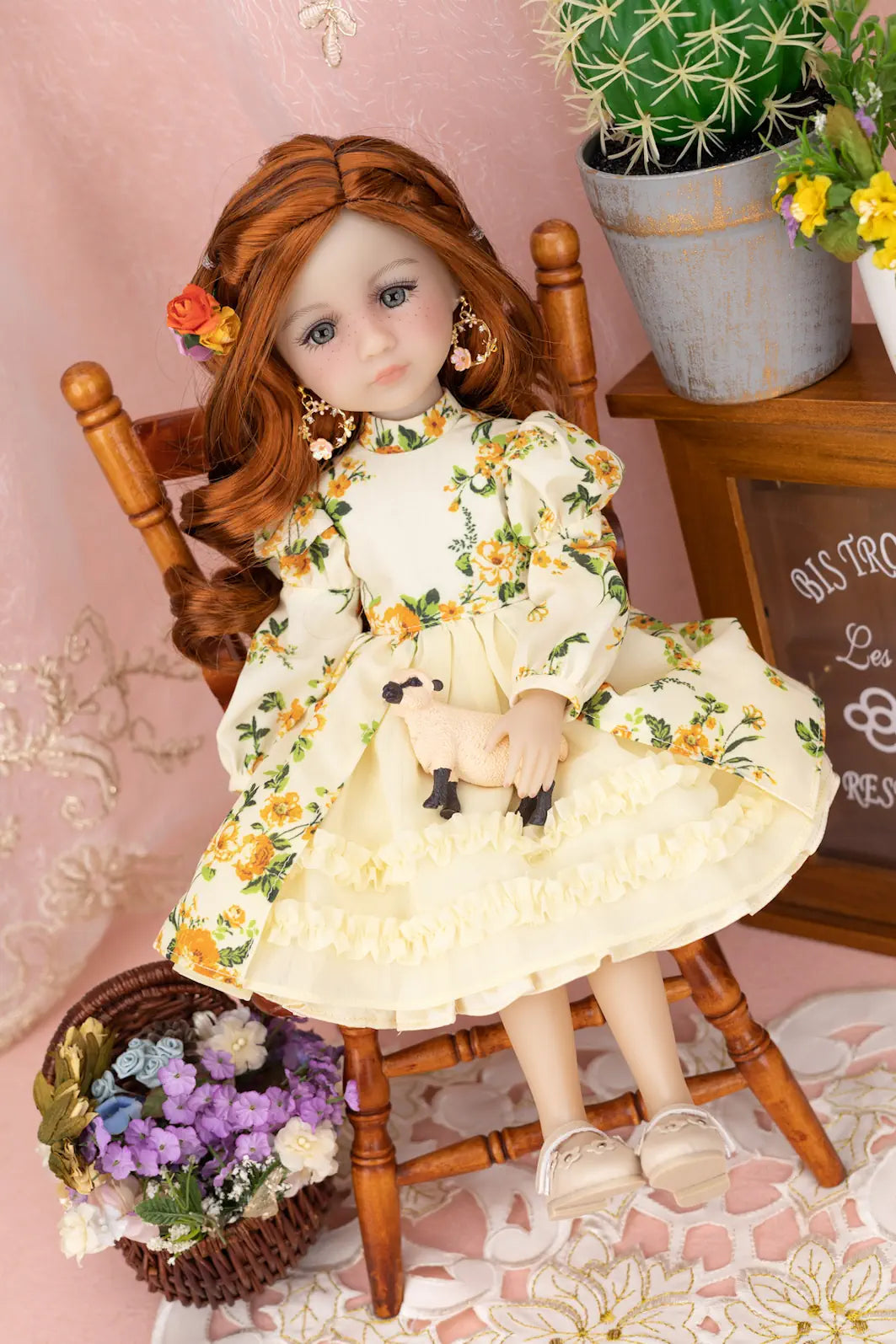 Doll in a floral dress sitting on a wooden chair with a pink background