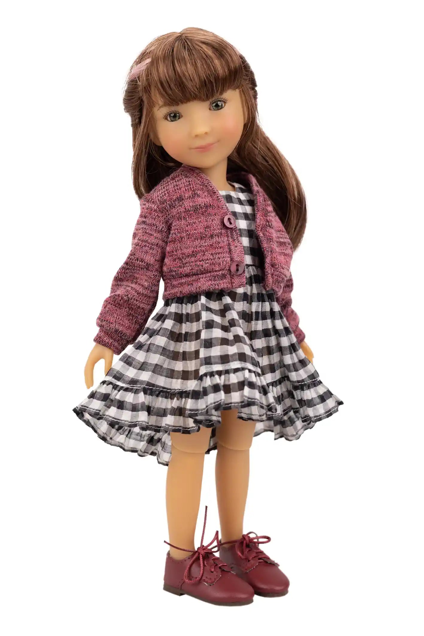 Doll wearing a pink jacket and checkered dress on a white background