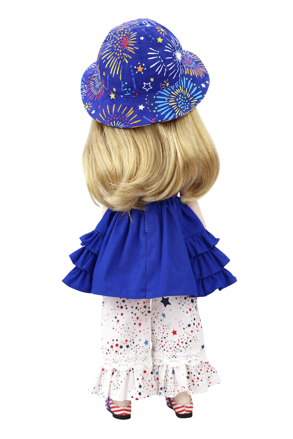 Doll wearing a blue dress with ruffles and a fireworks-patterned hat on a white background