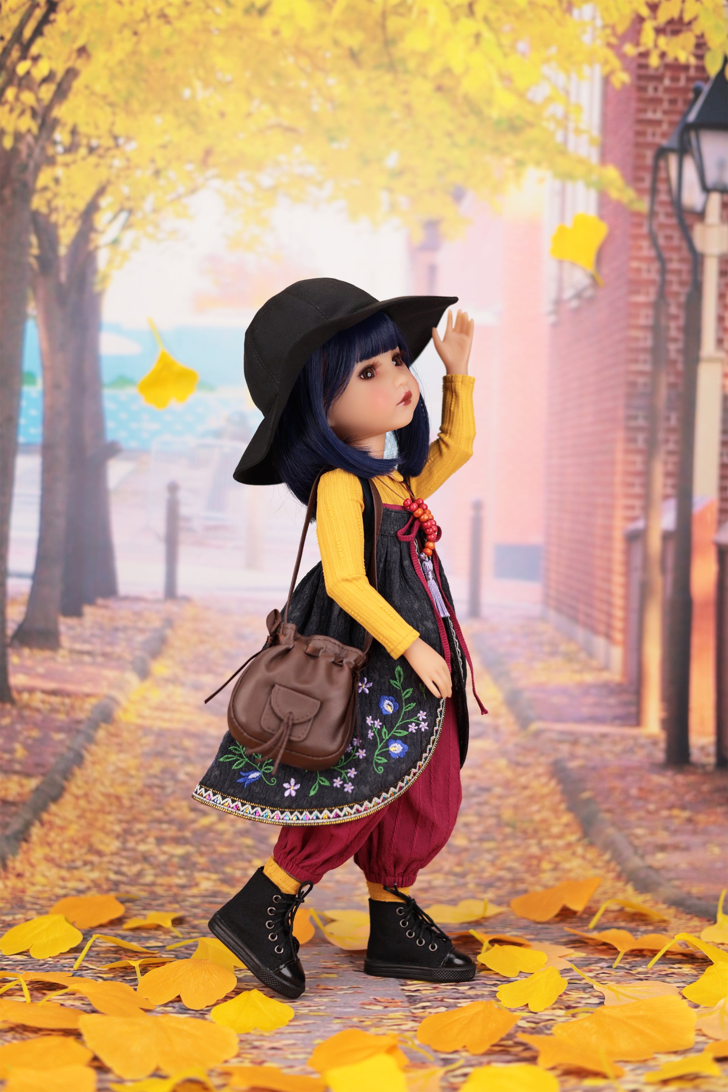 Doll in autumn setting with yellow leaves and brick building