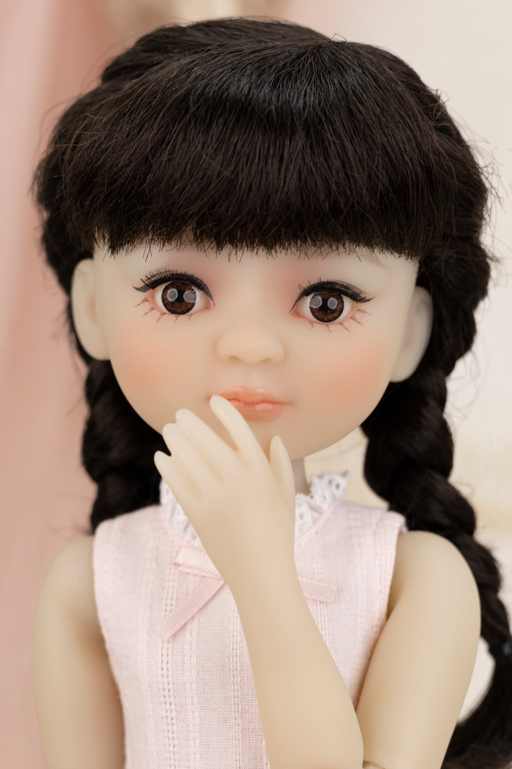 Close-up of a doll with long black hair and a light pink sleeveless top.