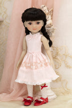 Doll wearing a white dress with lace details and red shoes in a decorative setting