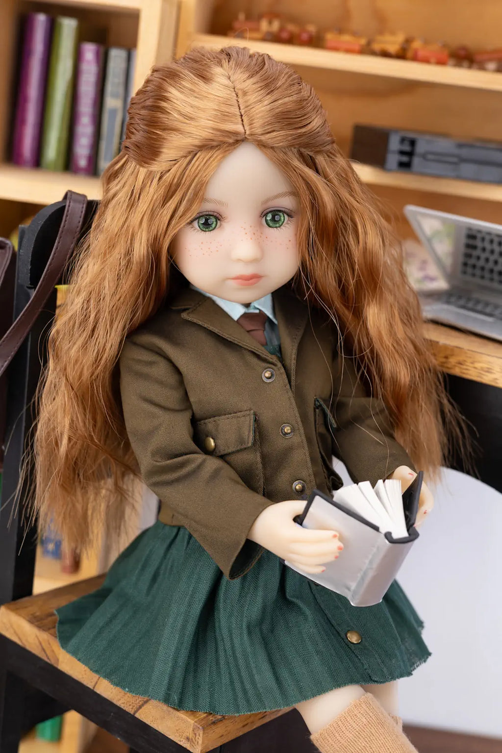 Doll with long brown hair wearing a school uniform sitting on a chair.