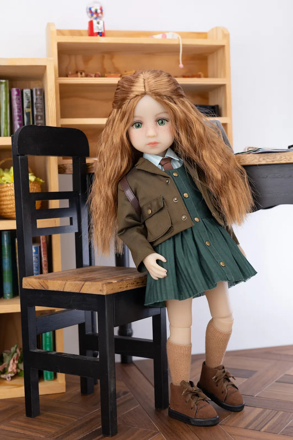 Doll in a green outfit standing next to a chair with a bookshelf in the background