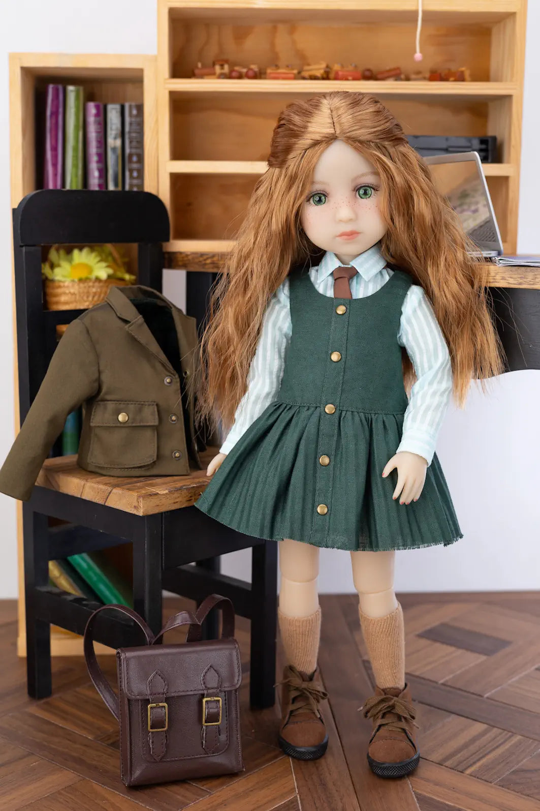 Doll in a green dress with a chair and books in the background