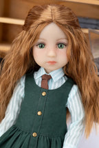 Doll with long brown hair wearing a green dress over a white shirt.
