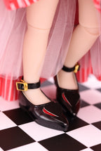 Black shoes with gold buckles worn by a person on a checkered floor.