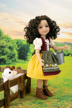 A doll with curly brown hair wearing a traditional German-style outfit with a yellow skirt, green apron, and white blouse, standing in a grassy field next to a small white sheep in a wooden pen.