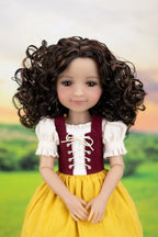 A doll with long, curly dark brown hair wearing a traditional-style dress with a maroon bodice, white ruffled sleeves, and a yellow skirt, posed against a blurred green landscape background.