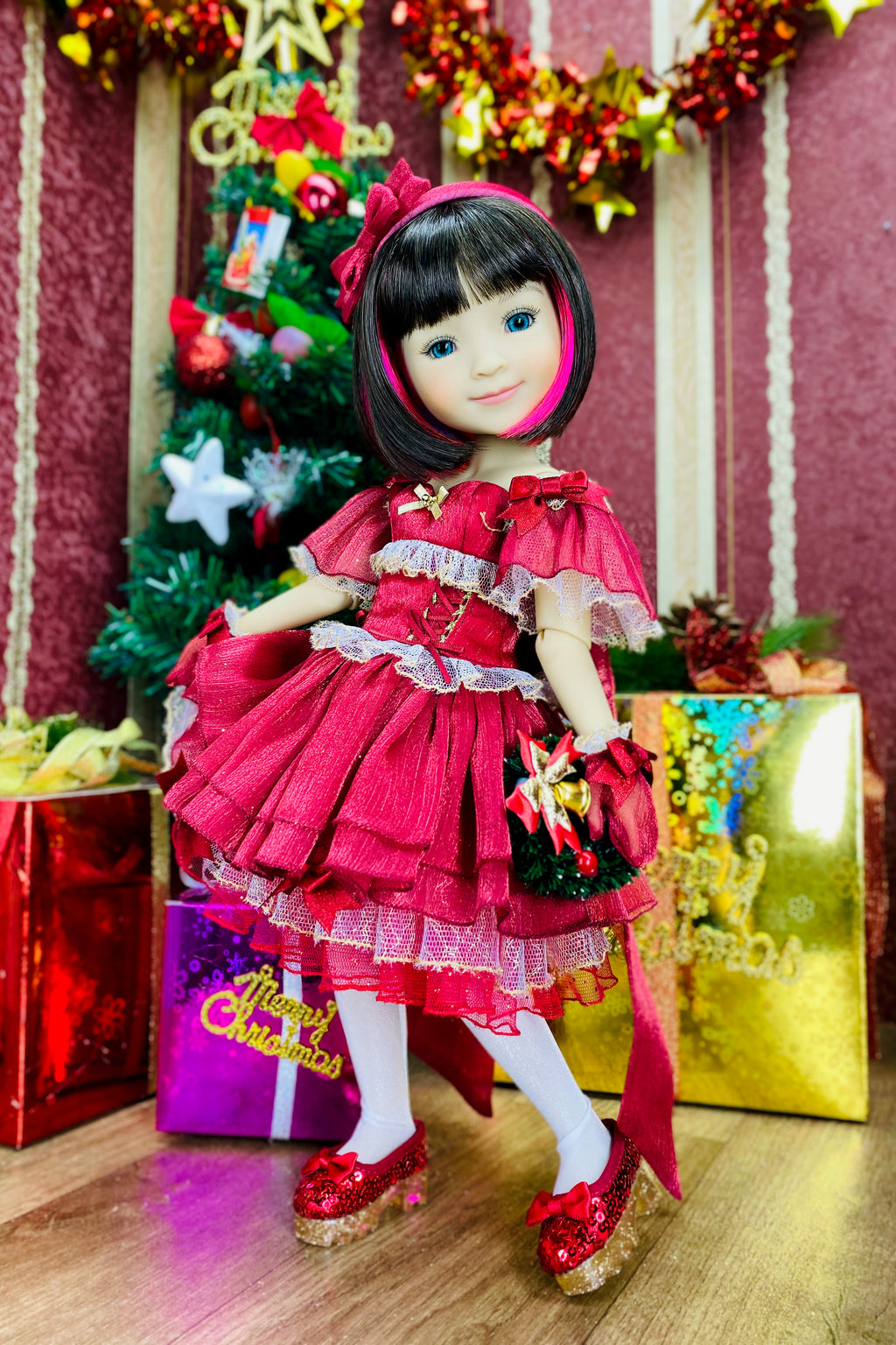 Doll in a red dress with a Christmas tree and presents in the background