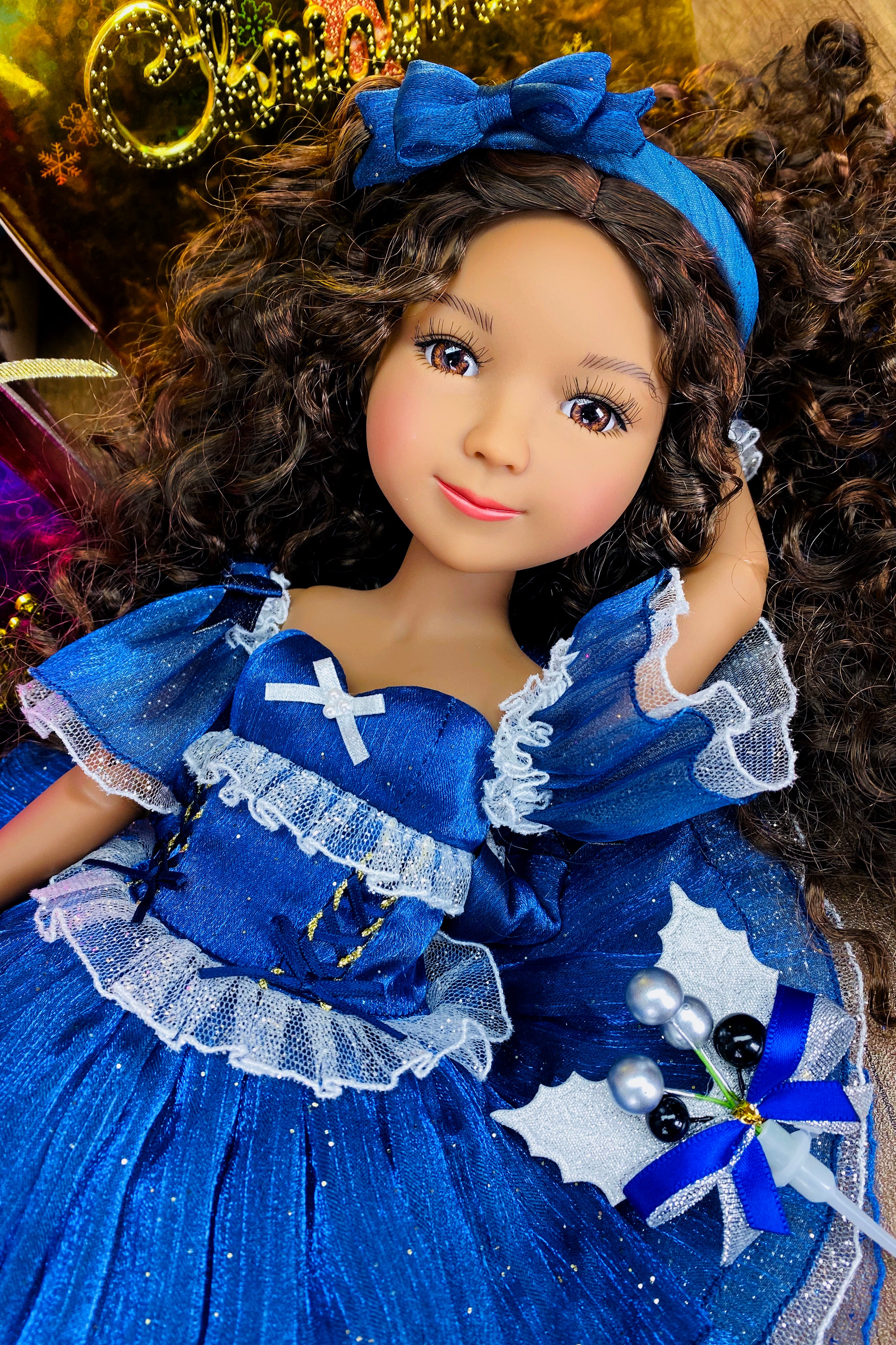 Doll in a blue dress with white details and a blue bow headband.