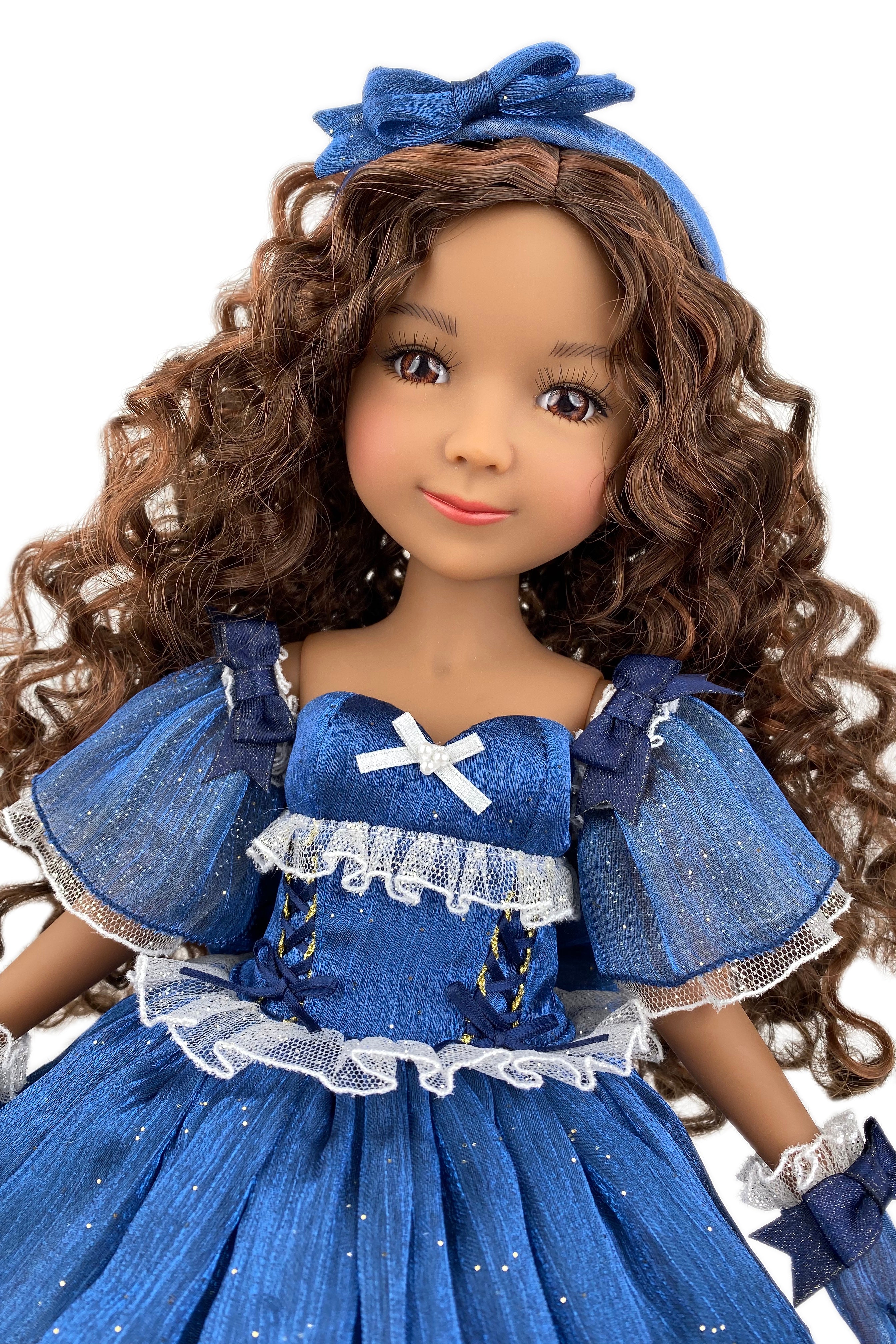 Doll in a blue dress with a bow headband on a white background